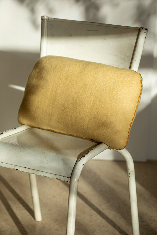 Pebble cushion in felted wool on a chair in the sun Pebble cushion in felted wool on a chair in the sun