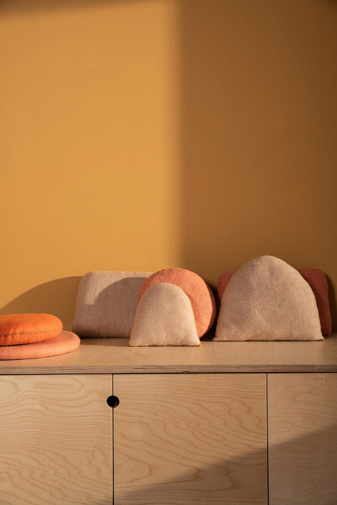 Coussin caillou en laine feutrée posé sur une chaise au soleil
