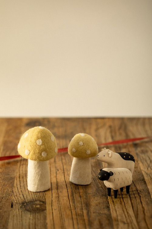 deux champignons à pois en laine bouillie accompagnés de figurines en bois