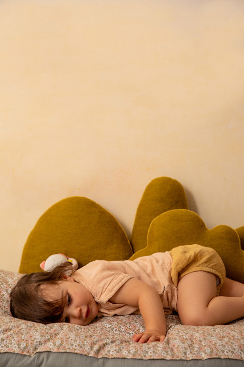 Petite fille se reposant entourée de coussins en feutre Petite fille se reposant entourée de coussins en feutre