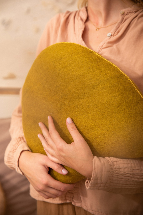 Femme tenant un coussin en laine feutrée dans ses mains Femme tenant un coussin en laine feutrée dans ses mains