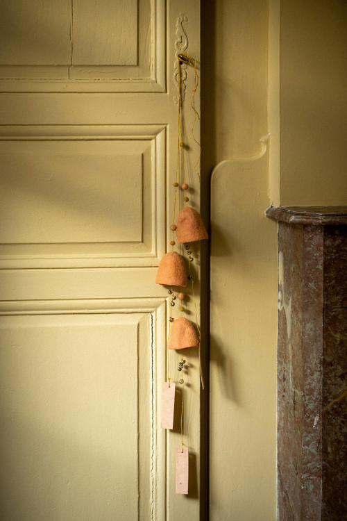 trio de cloches en laine suspendues à la poignées d'un porte ajoutant une touche colorée à la décoration