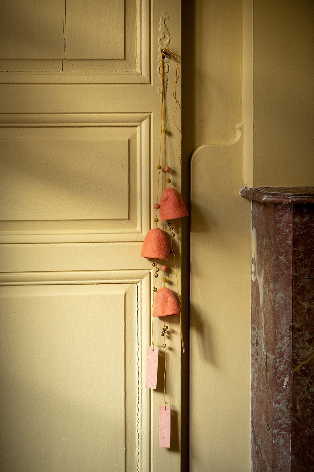 deux cloches en feutre suspendues à la poignées d'une porte pour un décoration poétique et colorée