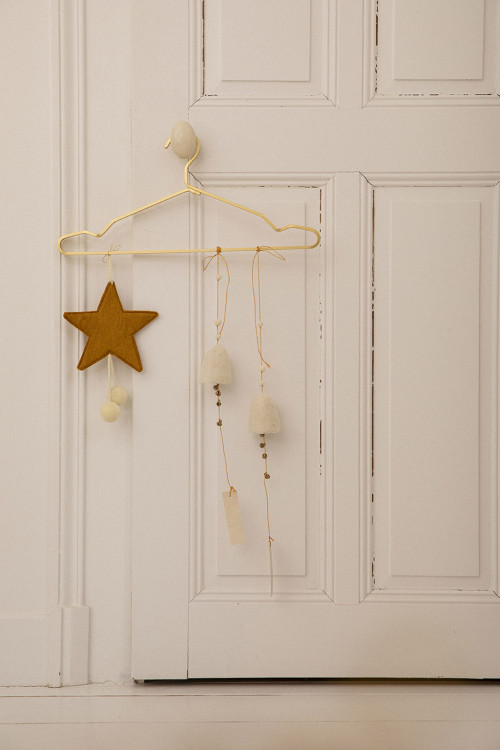 a gold felt star with white tassels hanging on a door handle for a colorful touch