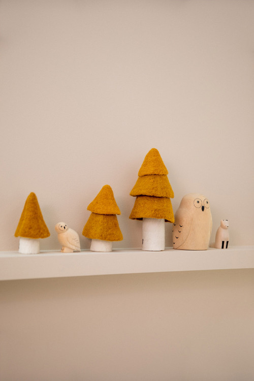 trois sapins or placés sur l'étagère d'une chambre pour une décoration feutrée et colorée trois sapins or placés sur l'étagère d'une chambre pour une décoration feutrée et colorée