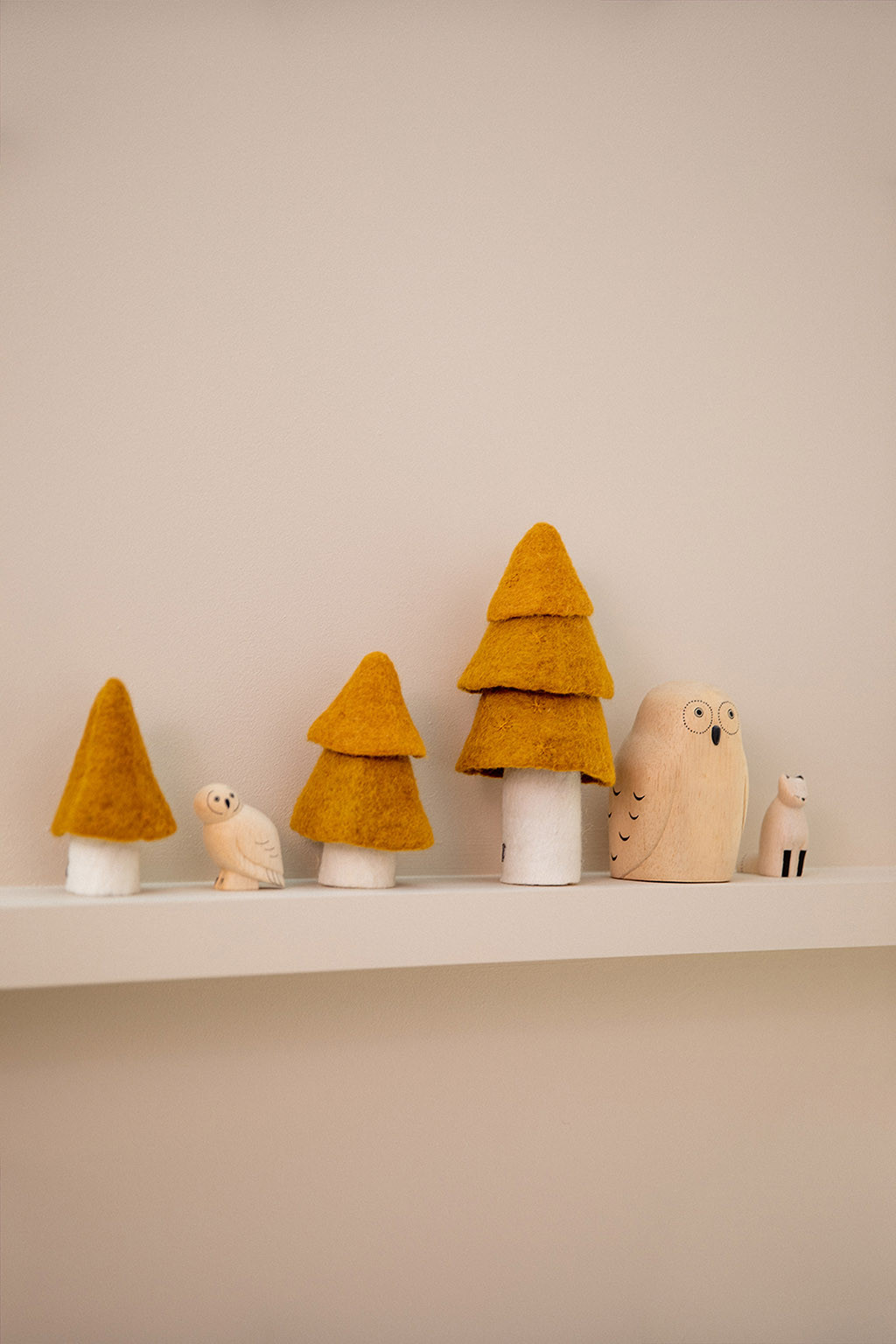 three gold trees placed on the shelf of a room for a felted and colored decoration