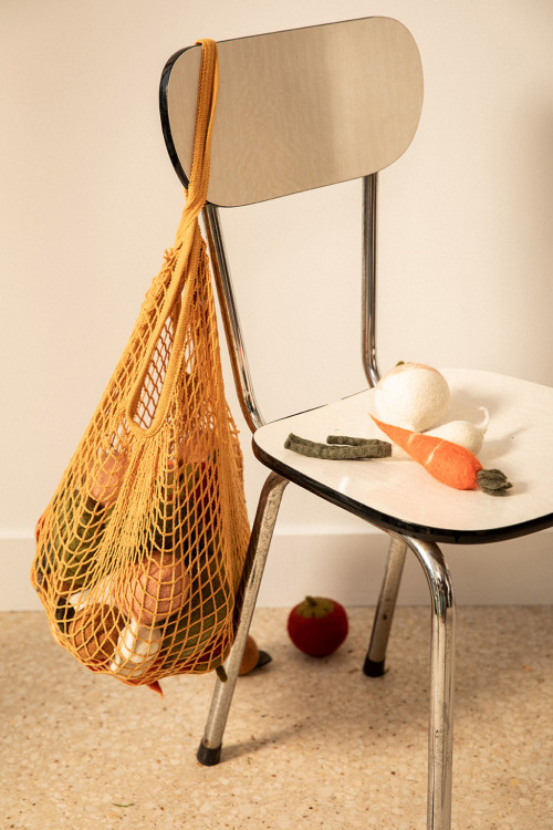 a net bag filled with handmade felted wool fruits and vegetables