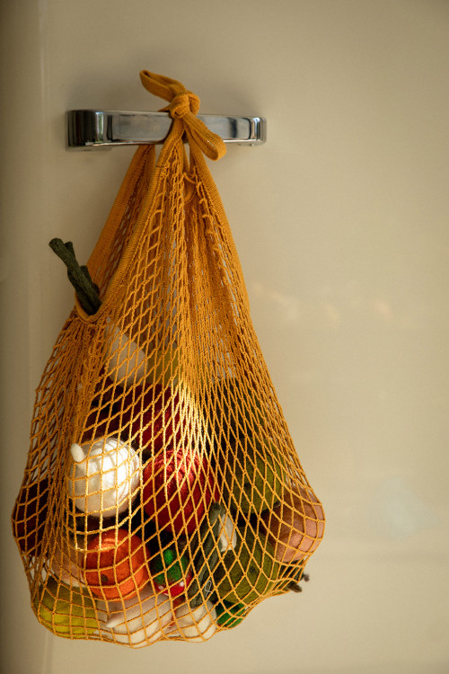a net bag filled with felted wool fruits and vegetables