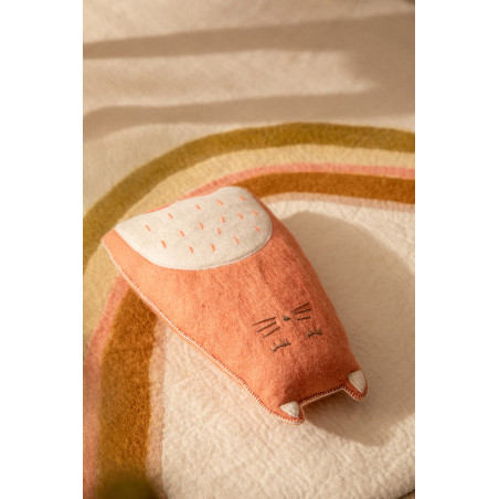 Un coussin chat rose posé sur un tapis en feutre