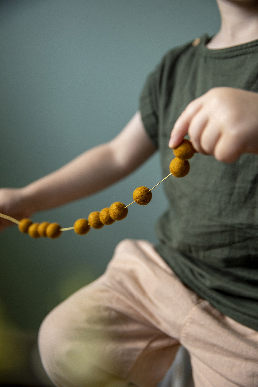 Felt pompons on a golden thread to create a playful garland