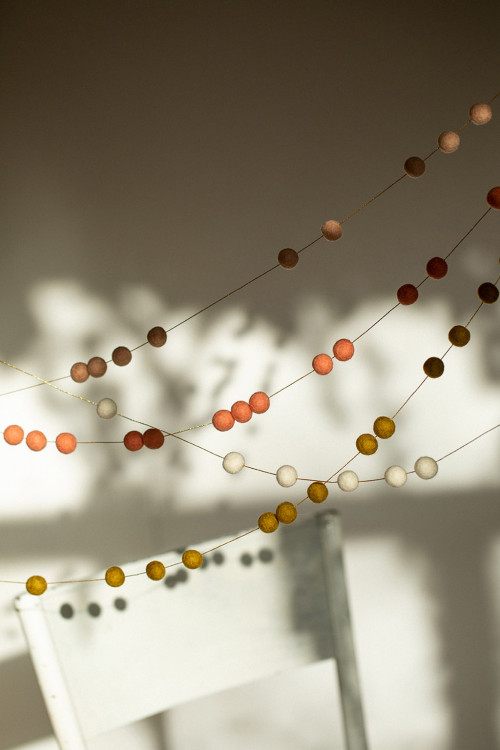 play of shadows and lights on a wall thanks to the delicacy of garlands of felt pompons play of shadows and lights on a wall thanks to the delicacy of garlands of felt pompons