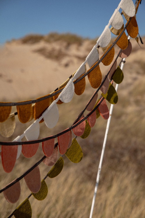 Felt garlands hung on a stick reminiscent of prayer garlands