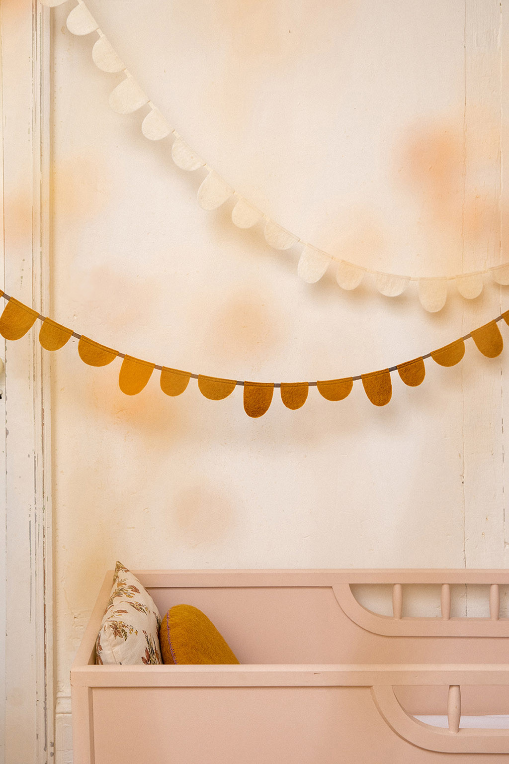 two white and mustard felt garlands placed above a crib