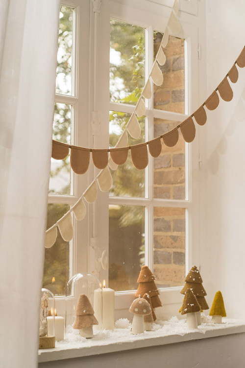 Felt trees and garland hanging in the window create a soft holiday atmosphere