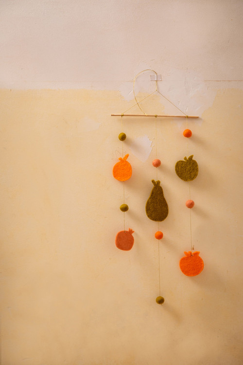 un mobile avec des fruits et légumes en feutre est accroché au mur pour une décoration joyeuse et colorée
