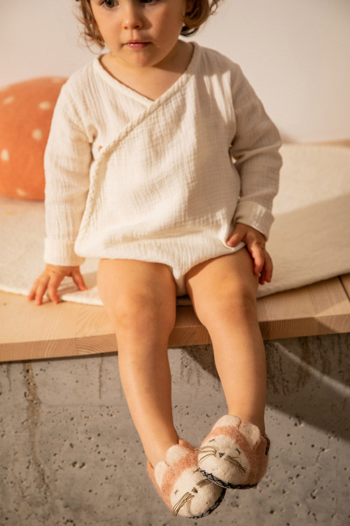une enfant porte des chaussons en feutre en forme de souris roses