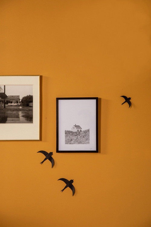 An ochre wall decorated with 2 black swallows in lokta paper