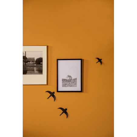 un mur ocre habillés de 2 hirondelles noires en papier lokta