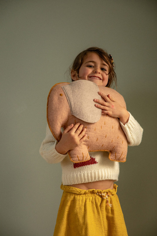 Petite fille tenant un coussin en laine en forme d'éléphant