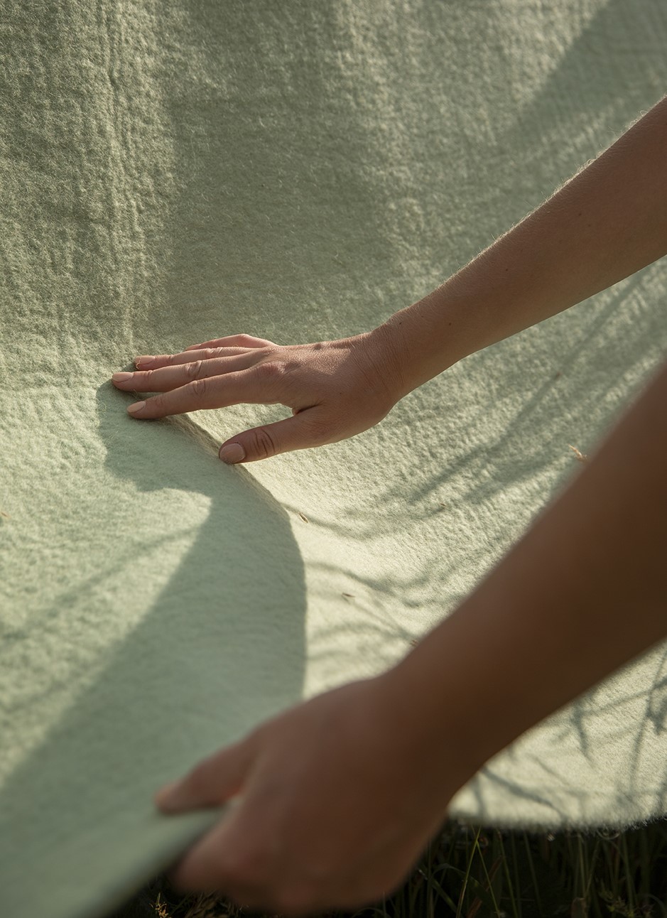 Main touchant un tapis en feutre de laine de couleur menthe
