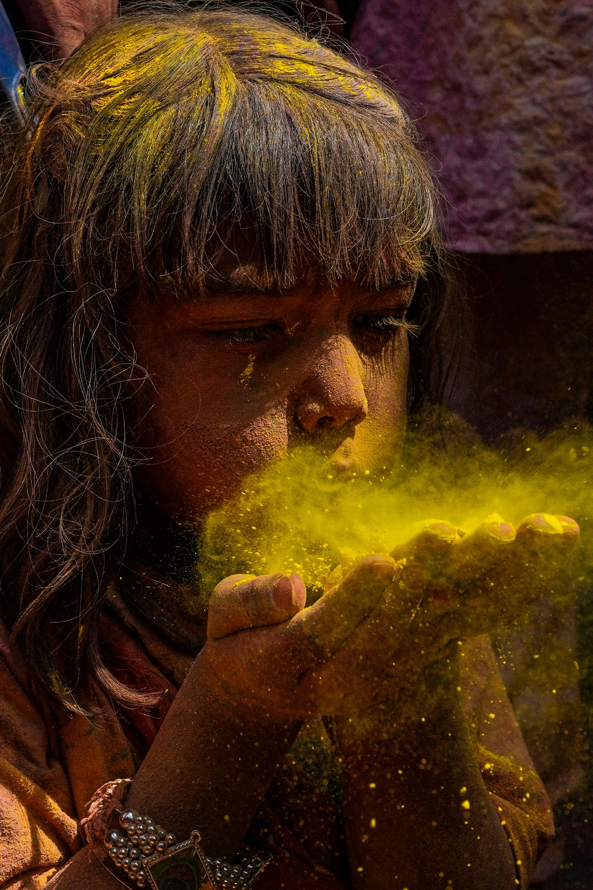 Petite fille soufflant sur de la poudre jaune pour célébrer Holi, un festival népalais