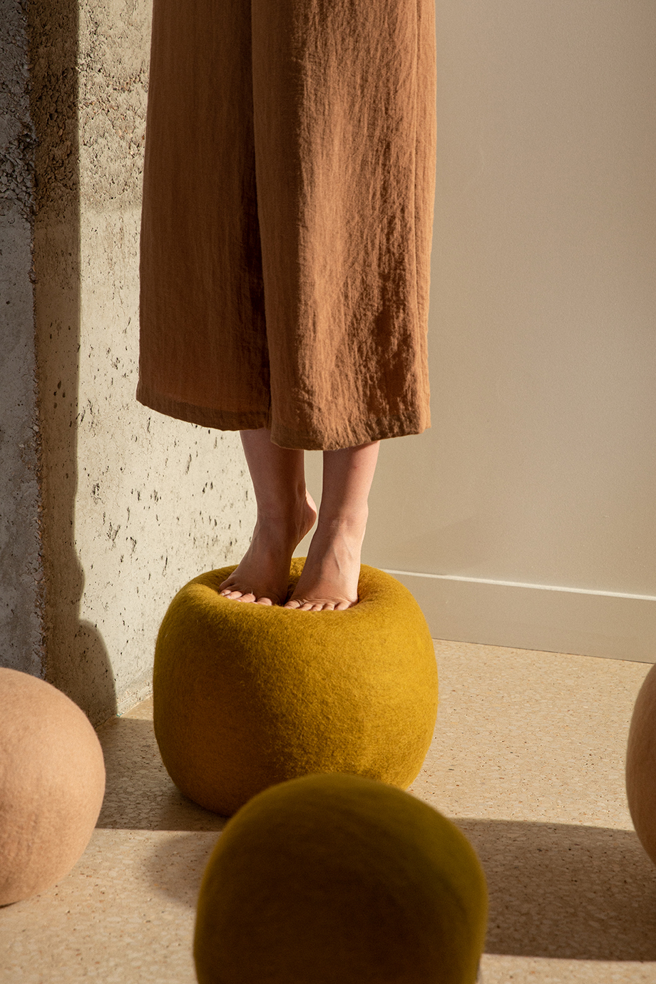 Femme debout sur un pouf rond vert en feutre de laine