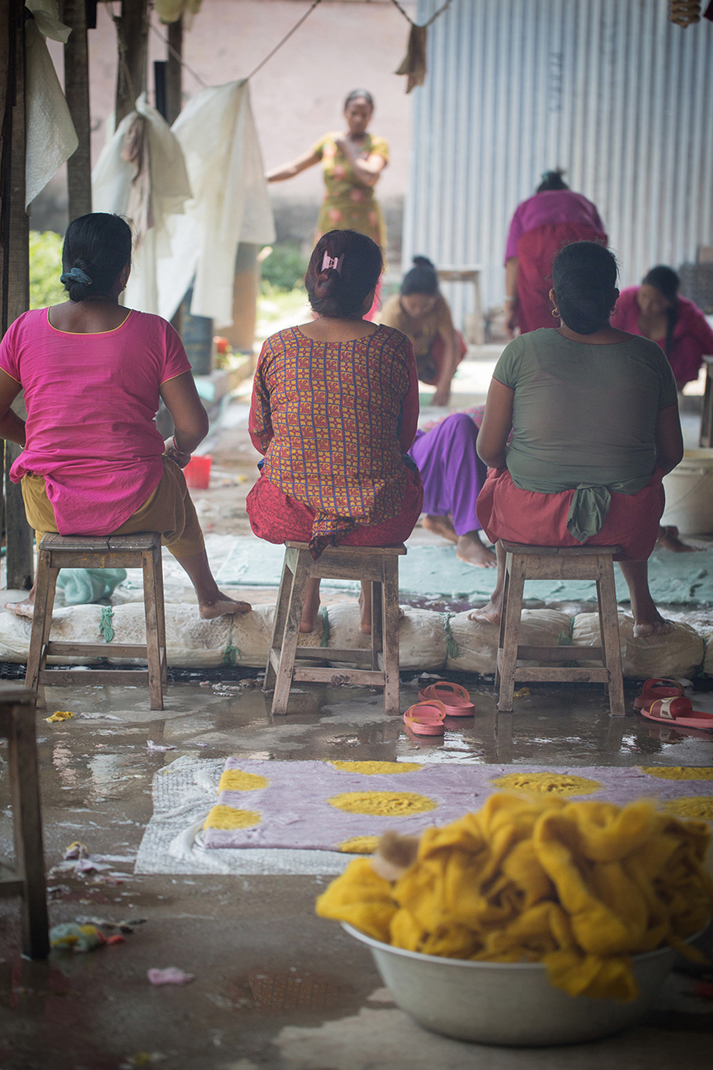 3 artisanes népalaises de dos dans les ateliers de production artisanale d'articles en feutre