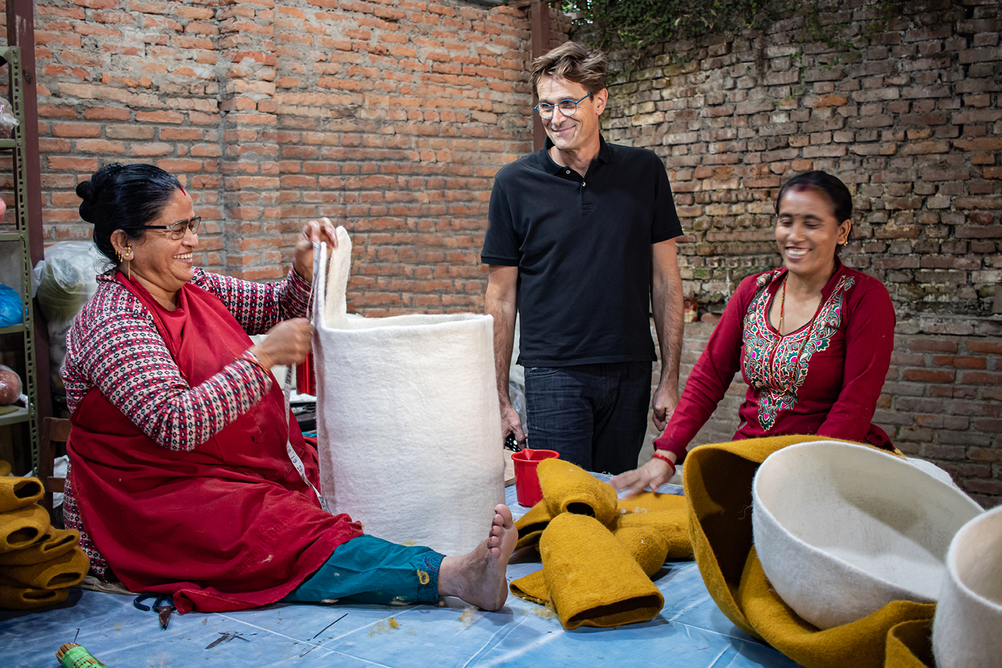 Artisane népalaise en train de façonner un panier de rangement haut en forme de lapin en feutre de laine