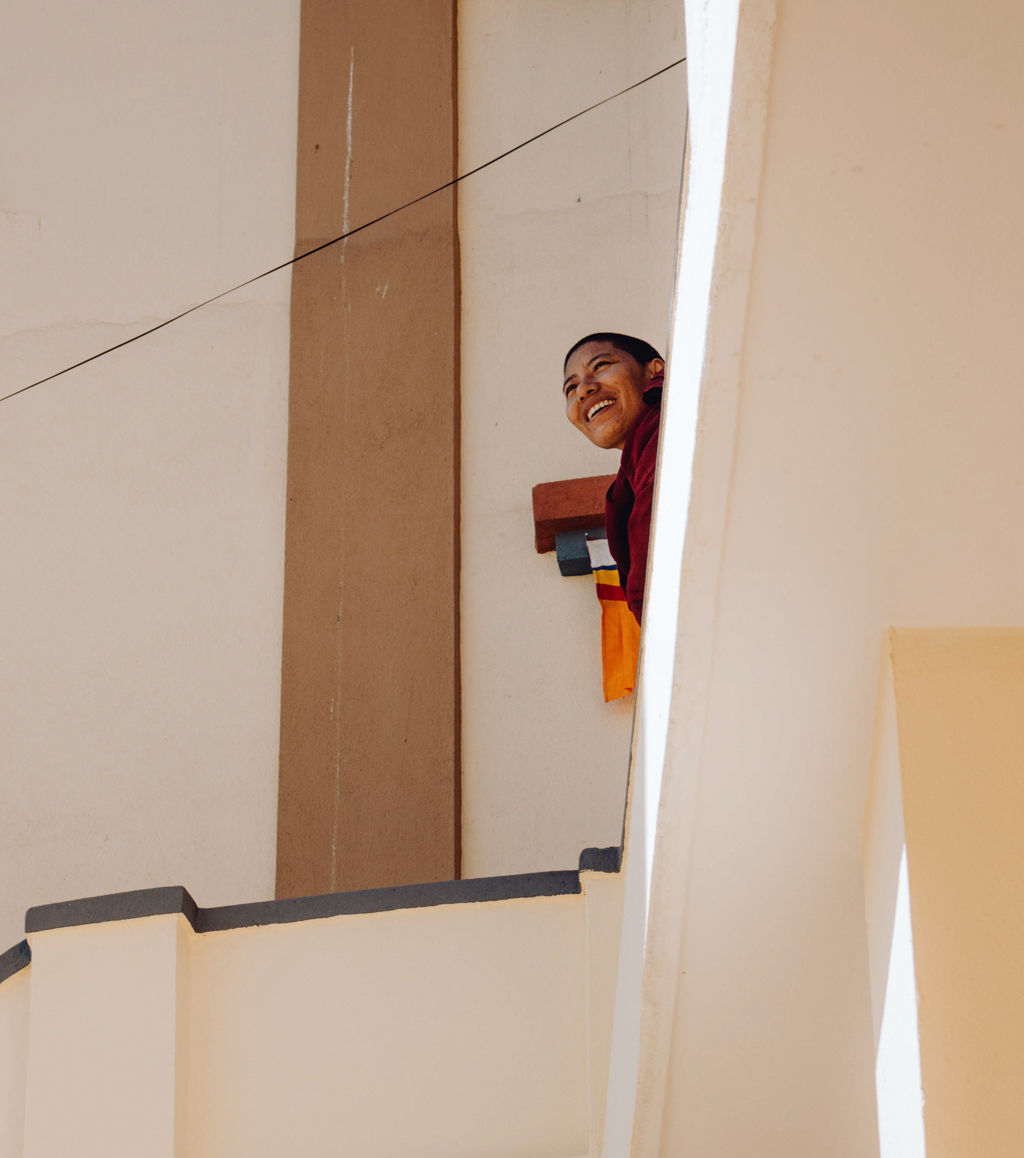 Moine népalais regardant vers la gauche en souriant depuis un balcon