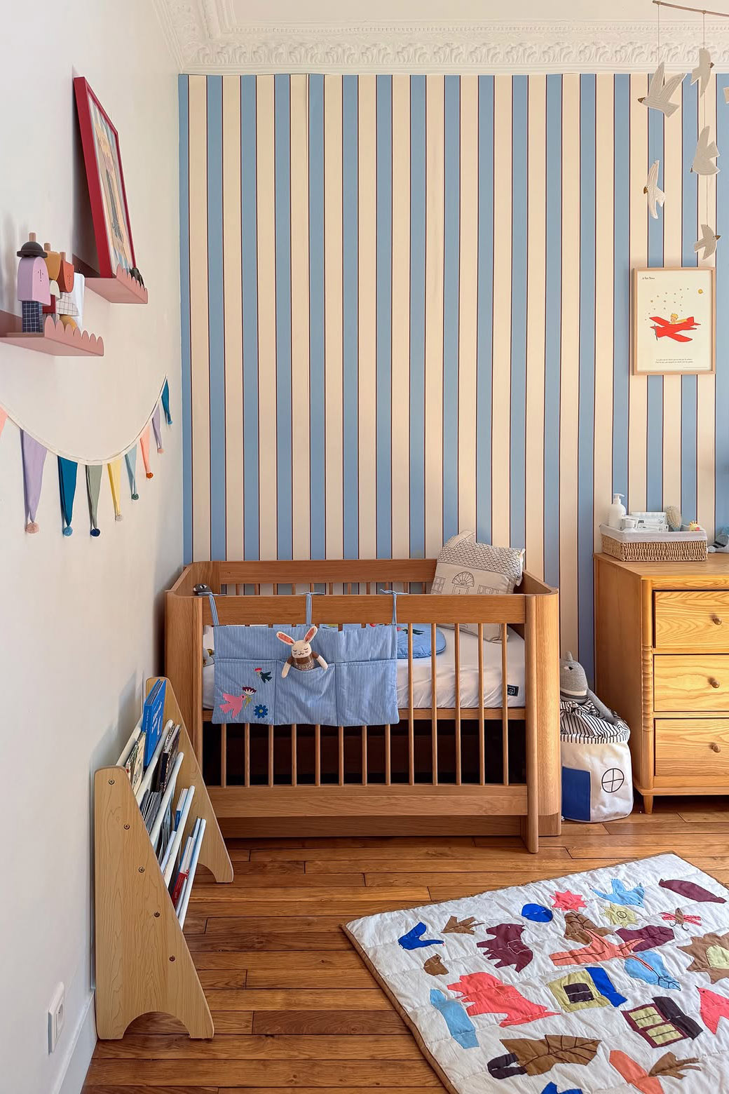 Chambre de bébé avec accessoires déco colorés et papier peint à rayures