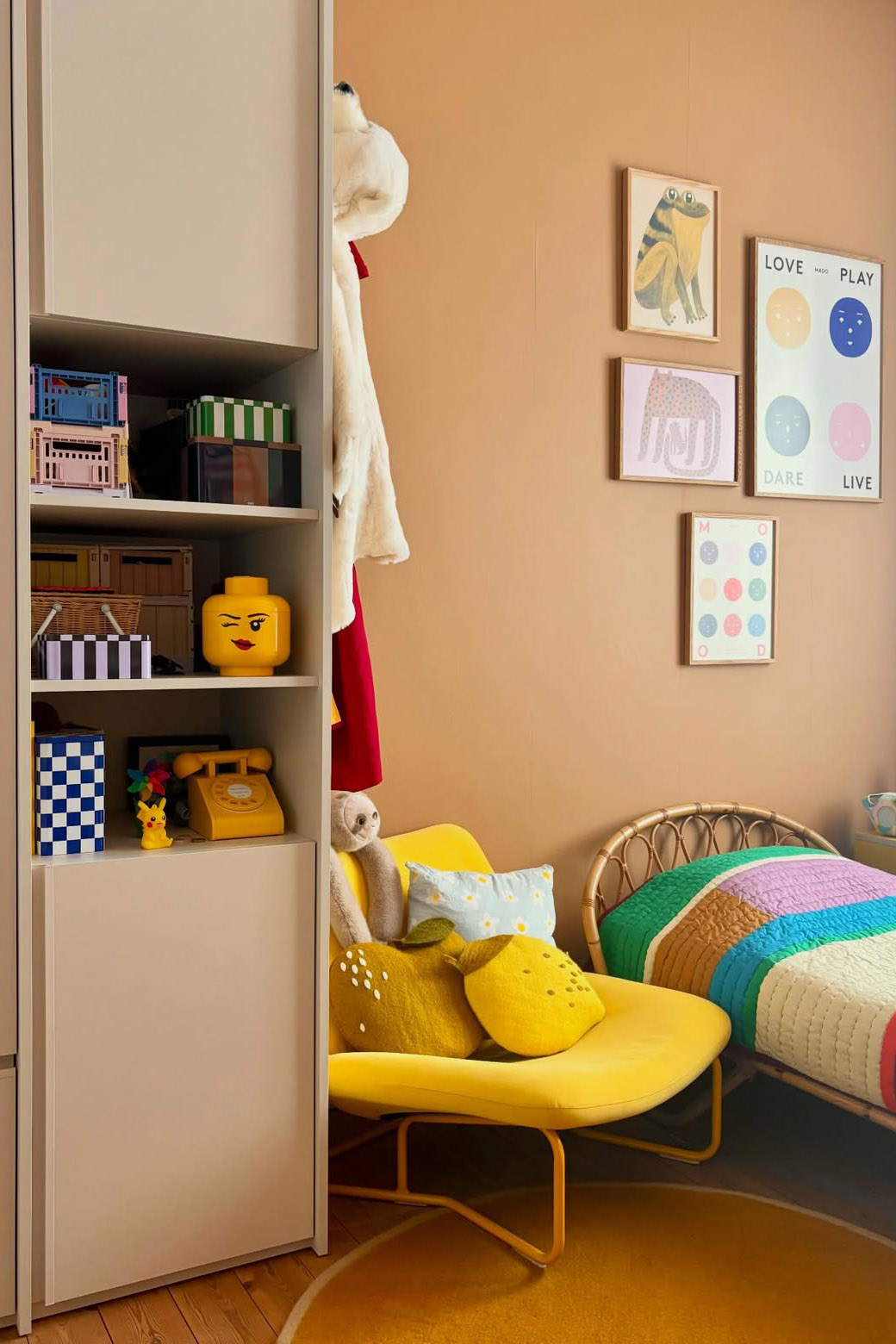 Chambre d’enfant colorée avec mobilier jaune, textiles multicolores et coussins ludiques en forme de fruits