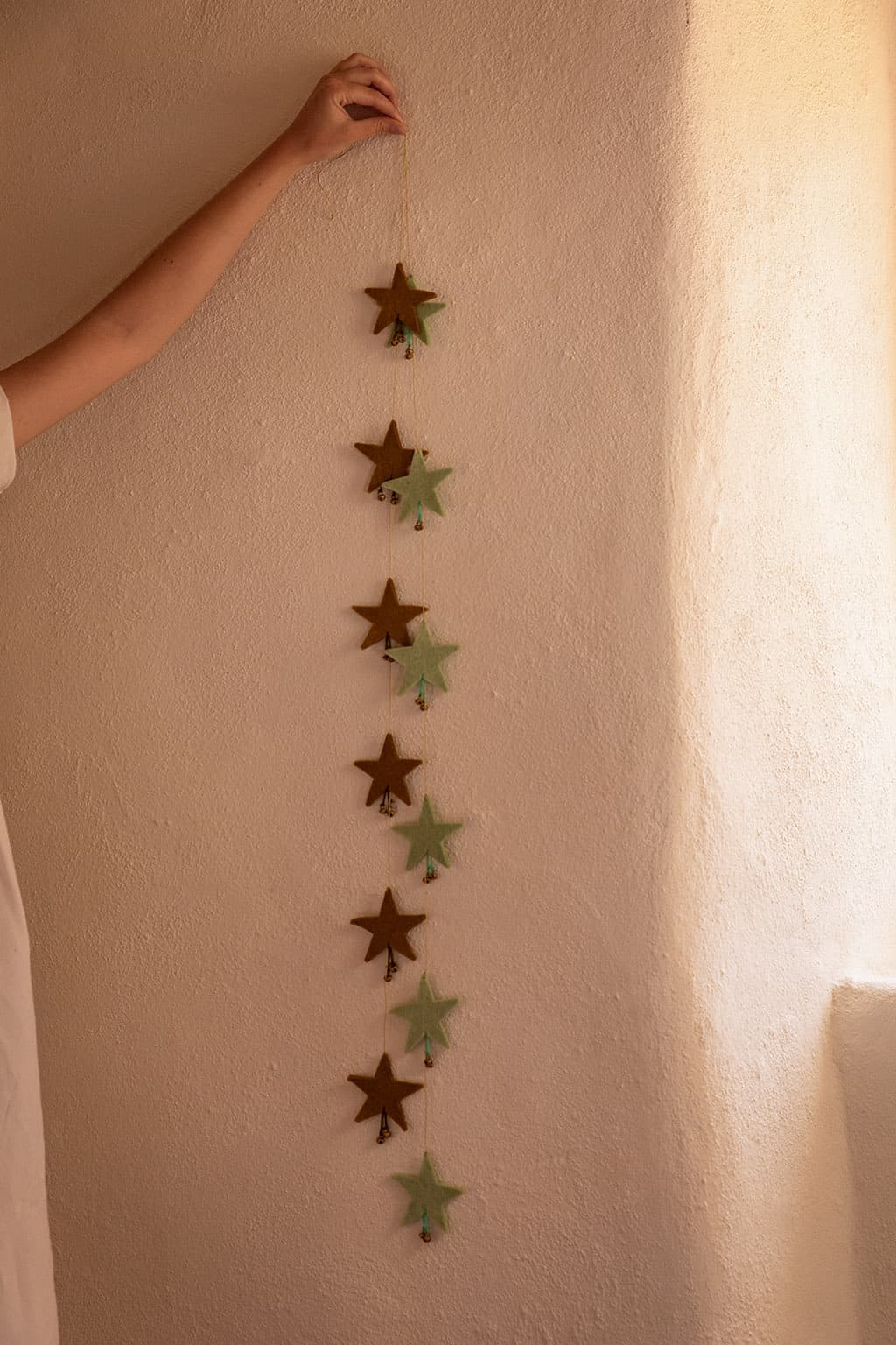Duo de guirlandes d'étoiles vert pistache et vert menthe en feutre pour décorer un mur en pierre