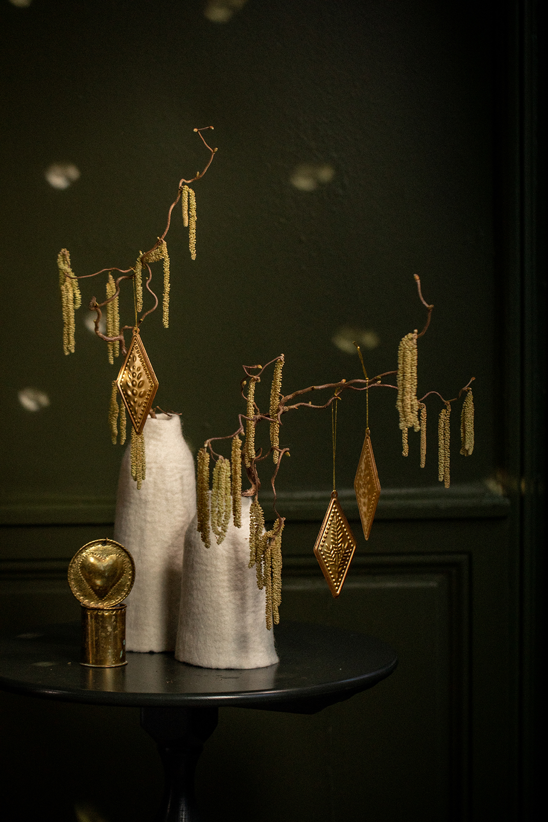 Des branchages de Noël disposés dans 2 vases blancs en laine feutrée pour une décoration de Noël éthique et chaleureuse