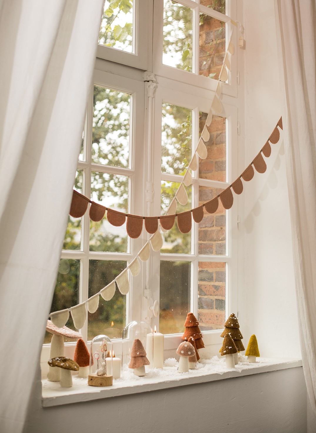Petits objets de décoration de Noël en feutre disposés sur le rebord d'une fenêtre pour une ambiance magique