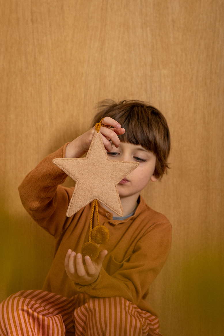 Petit garçon jouant une décoration étoile en feutre et laine