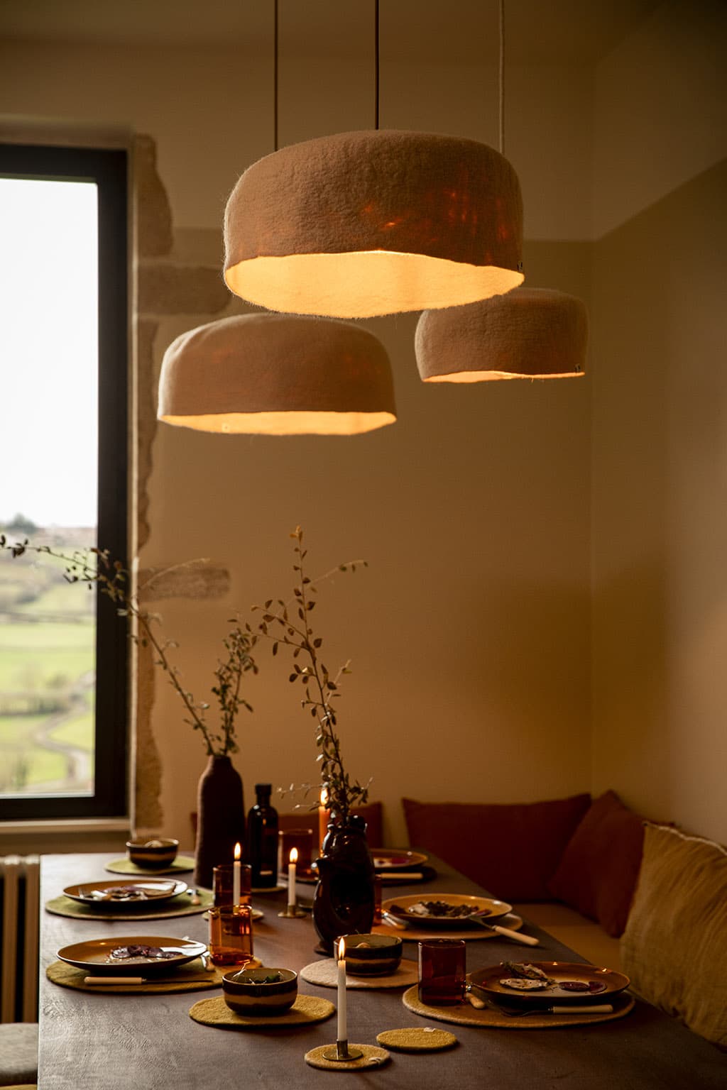 Luminaires en laine rose suspendus au dessus d'une table à manger en bois