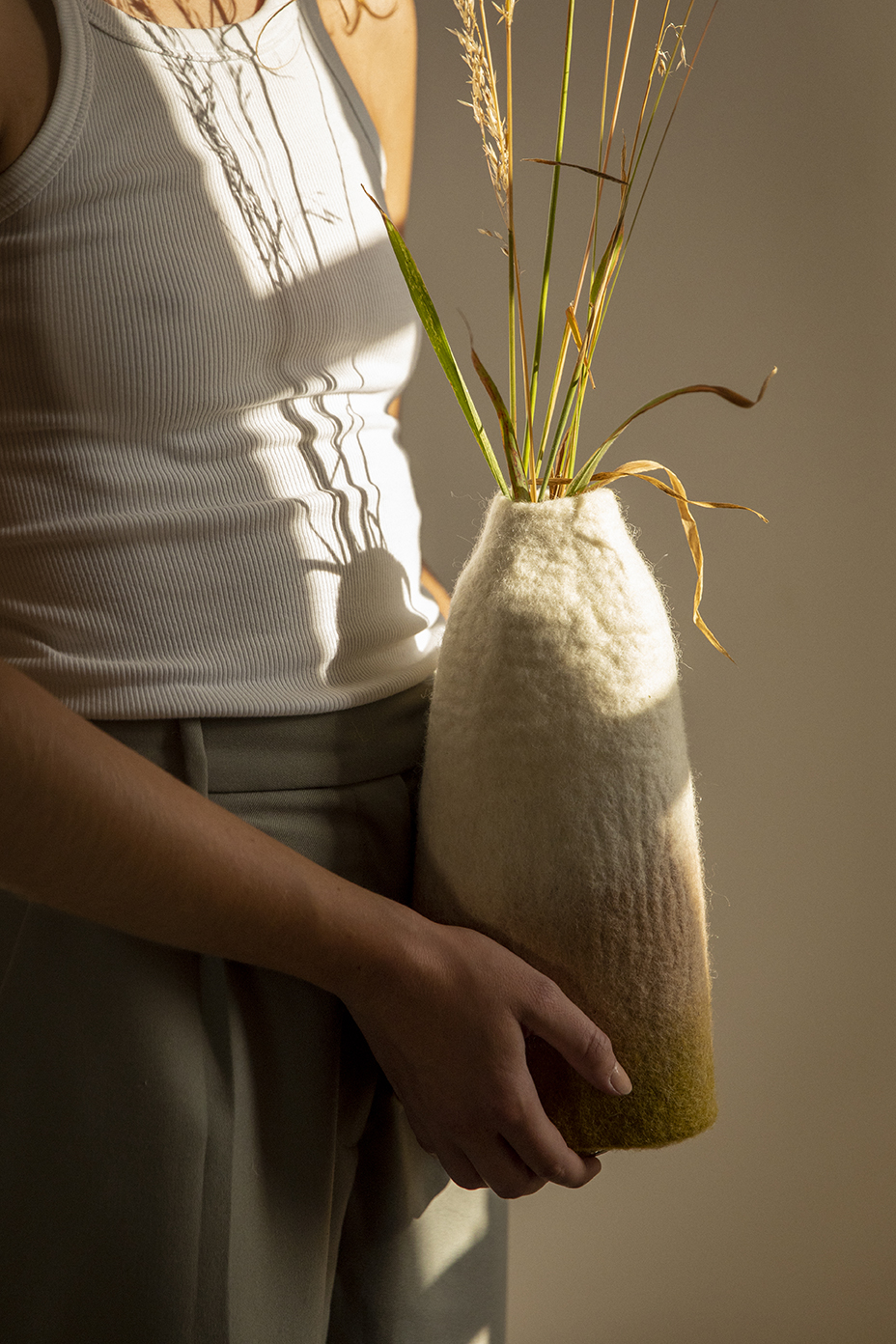 Femme tenant dans ses mains un vase tricolore en feutre de laine