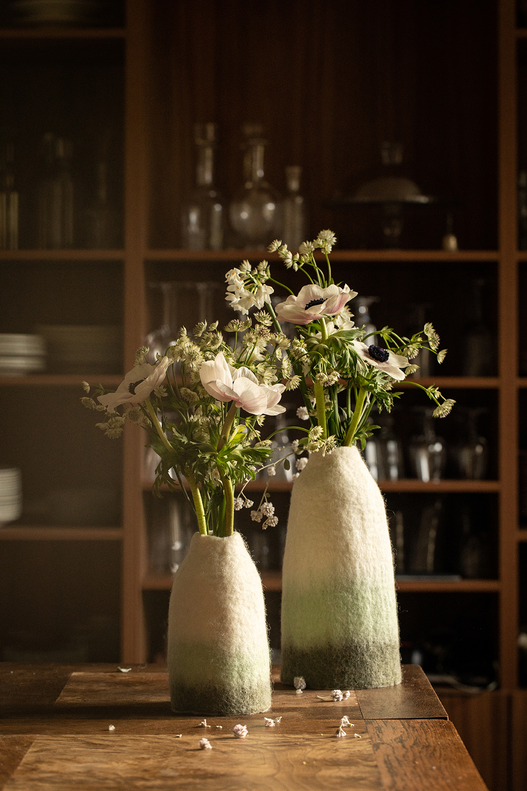 Duo de cache-vases tricolores blancs verts et menthes en laine feutrée posés sur une table