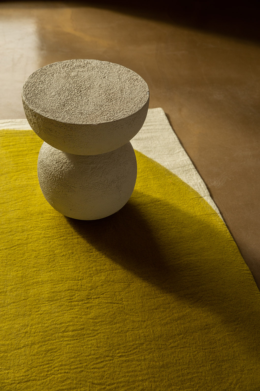 Tapis en laine et tabouret au fini brut pour un contraste des matières