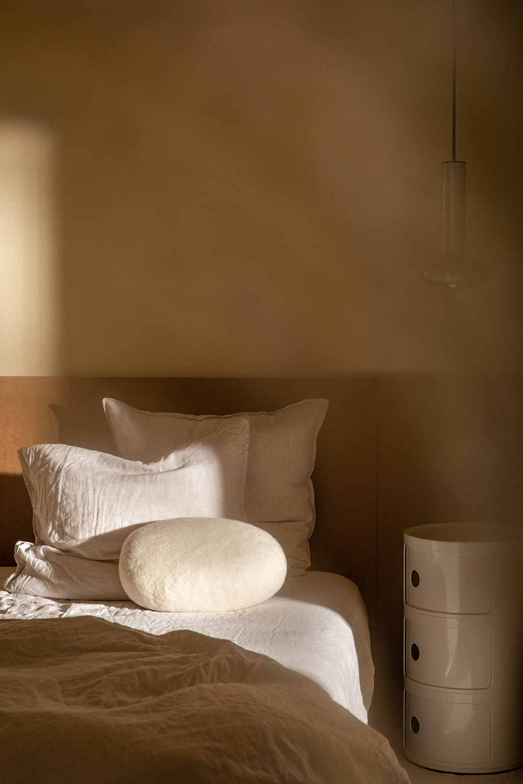 Coussin blanc en laine en forme de galet pour décorer le lit