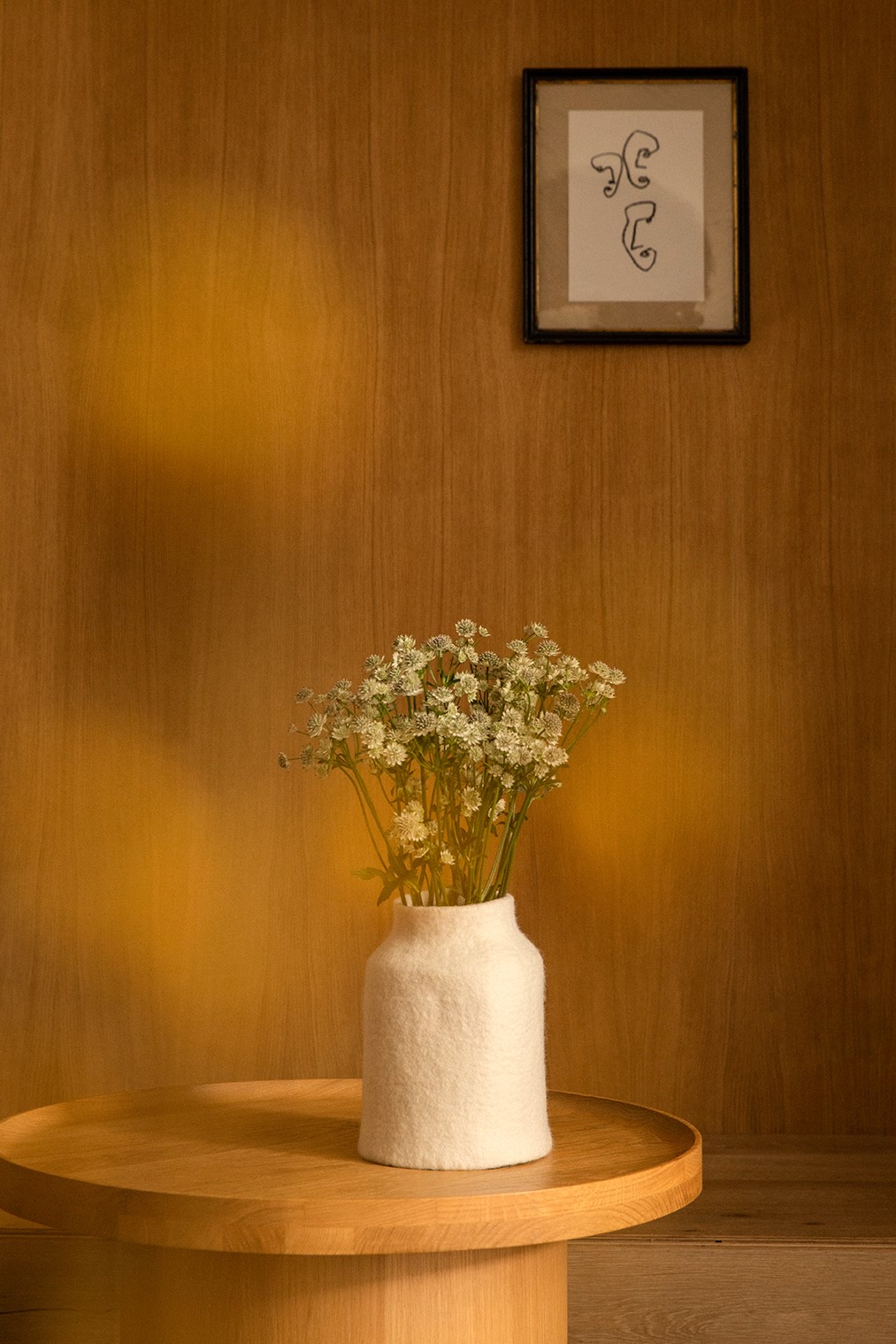 Cache-vase organique et minimaliste en feutre sur la table basse ronde en bois