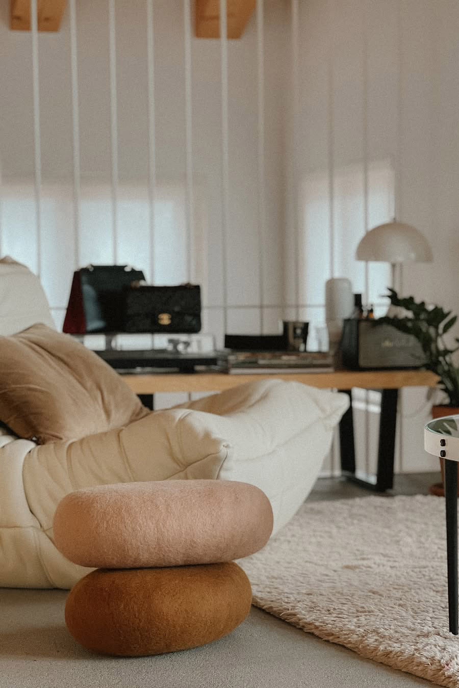 Duo de coussins ovales ocre et rose en laine au pied d'un canapé design en cuir blanc