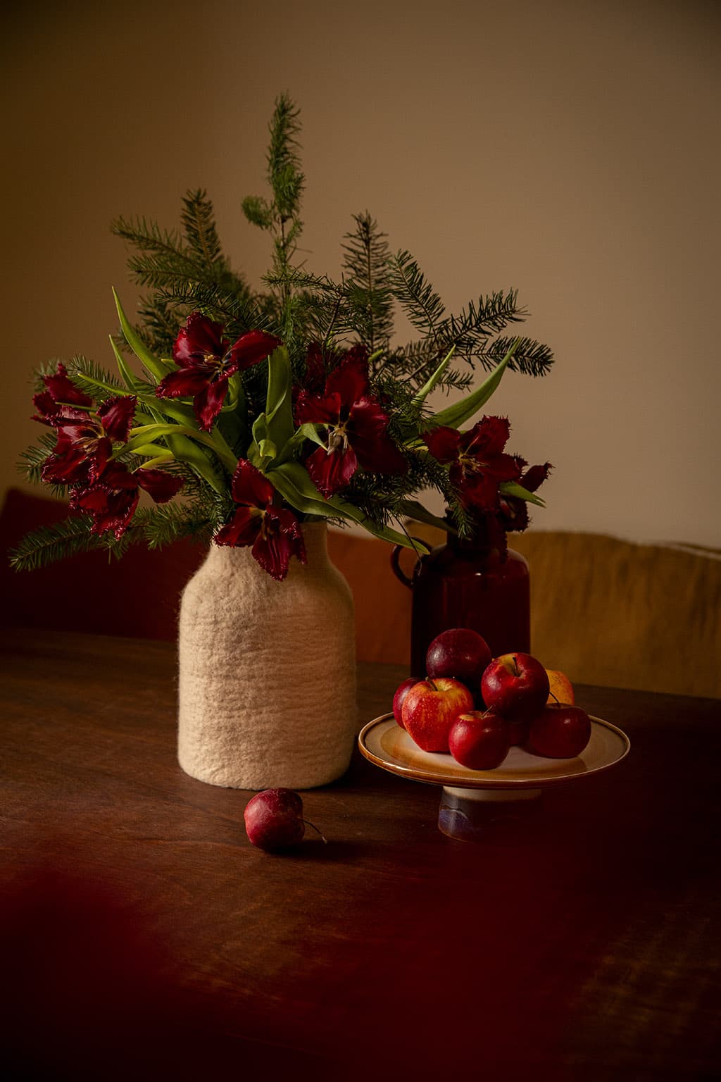 Vase rose poudré et fleurs bordeaux pour un joli contraste sur la table de salle à manger