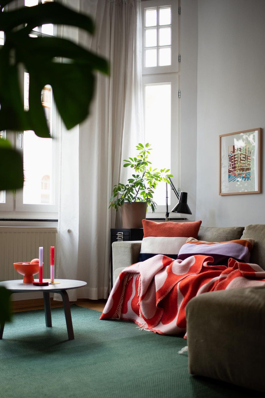 Plaid rouge posé sur un canapé et tapis vert pour une décoration authentique du salon