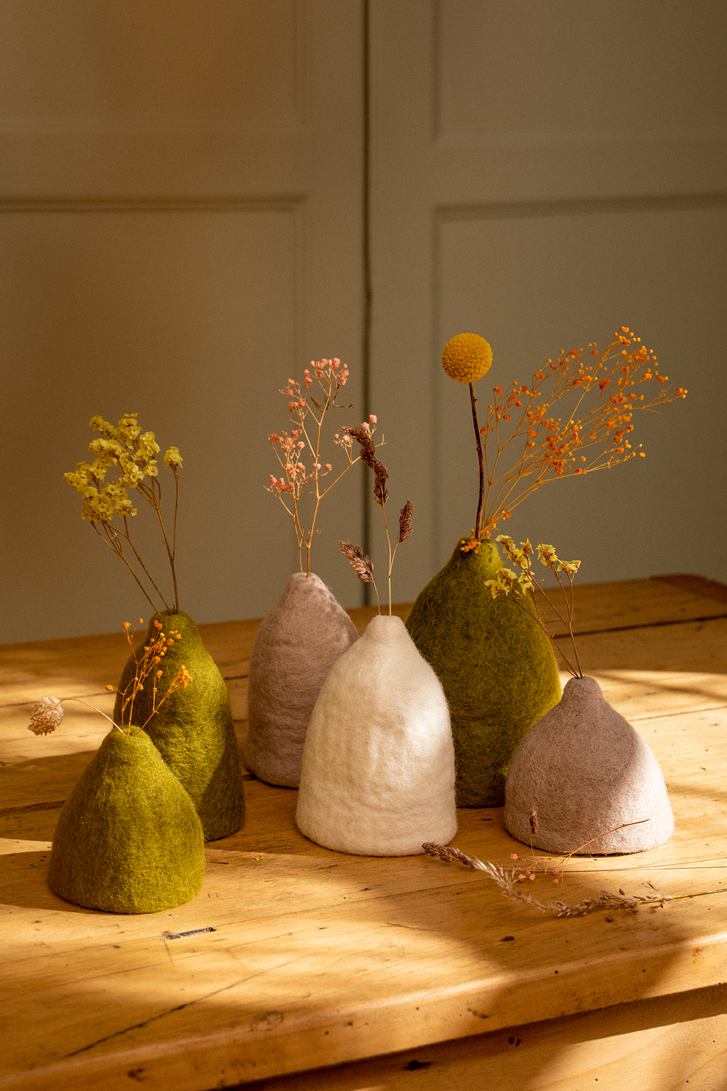 Assortiment de petits soliflores en laine feutrée sur une table en bois