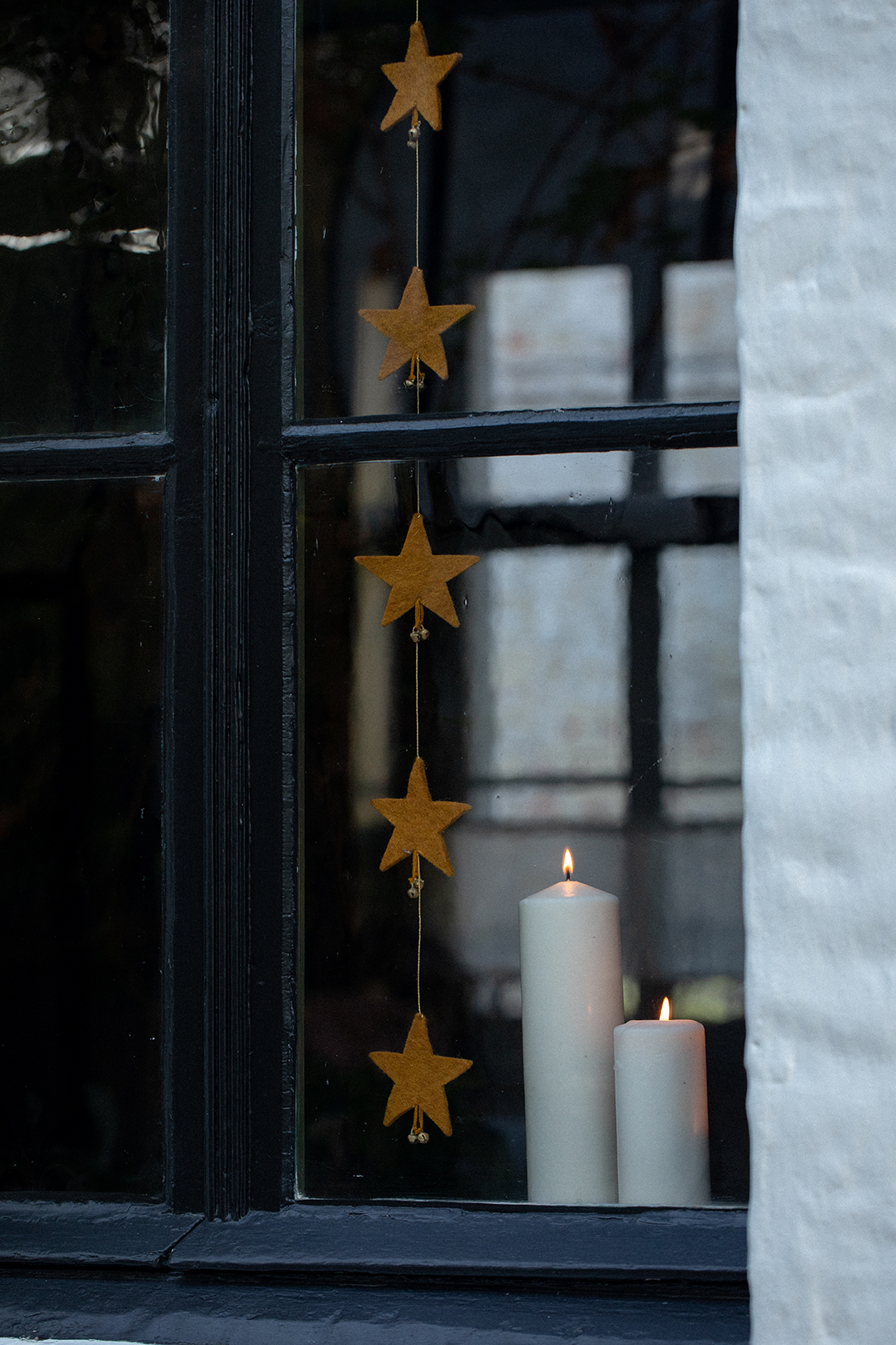 Guirlandes de 6 petites étoiles dorées en feutre accrochée devant une fenêtre pour une décoration poétique