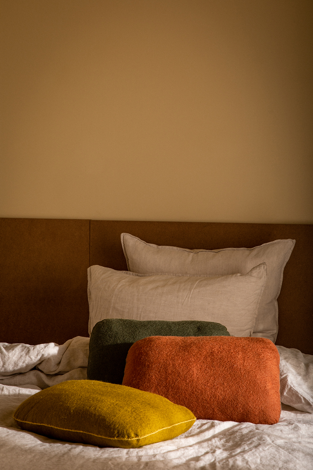 Trio de coussins rectangulaires en laine feutrée posés sur un lit