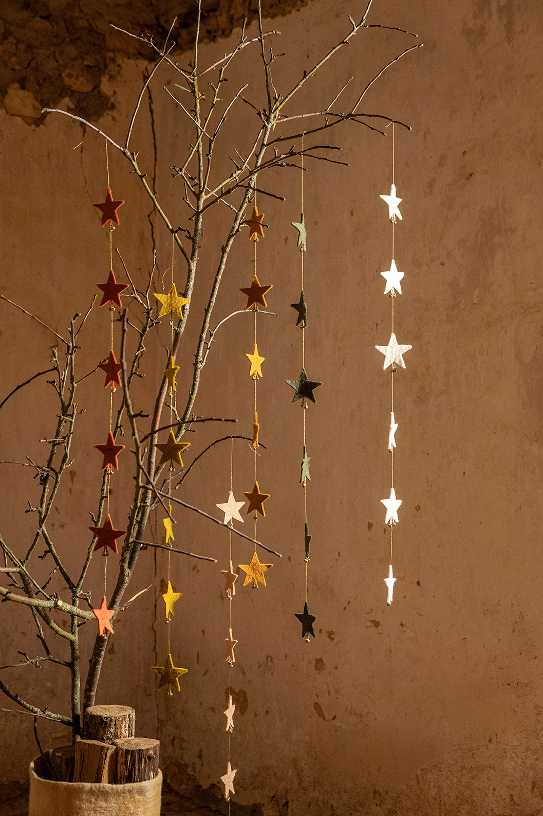 6 guirlandes d'étoiles en laine feutrée accrochées dans un arbre pour une décoration de Noël responsable
