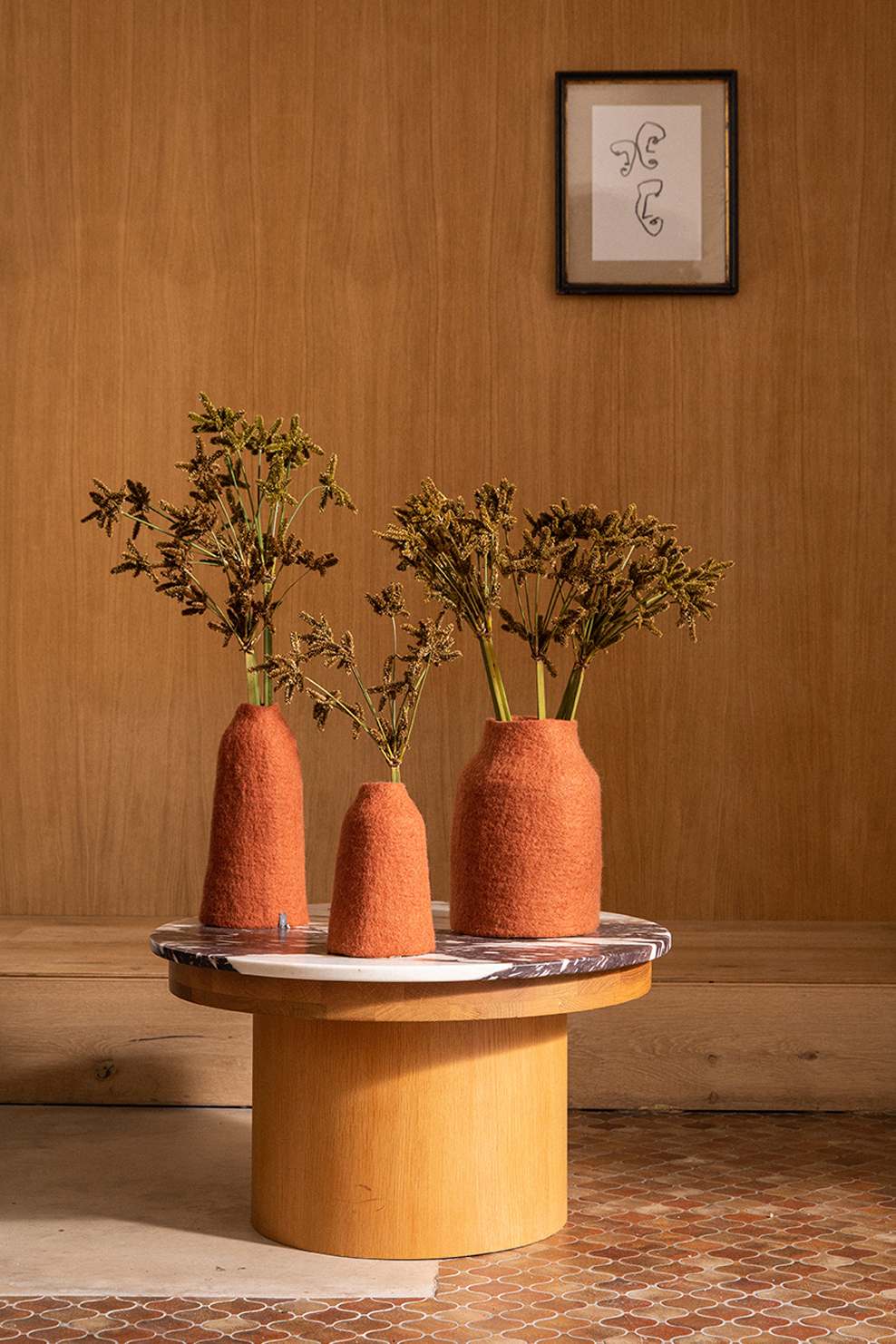 Trio de vases en laine de mouton rouges posés sur une table basse ronde pour une décoration élégante