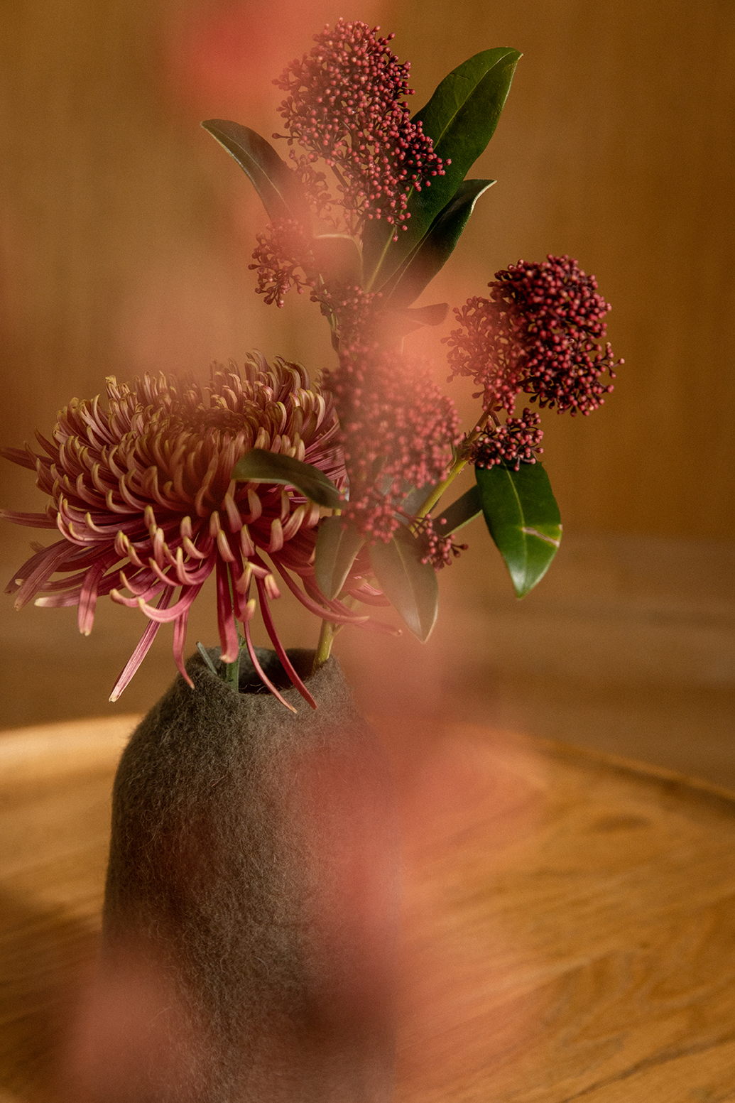 Des fleurs dans un vase vert en laine feutré posé sur une table basse pour une élégante décoration